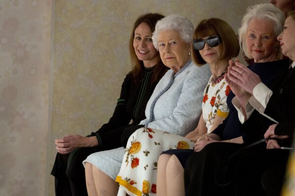 
              CAPTION CORRECTS THE USAGE - Britain's Queen Elizabeth, second left, sits next to fashion editor Anna Wintour, third left, and Caroline Rush, chief executive of the British Fashion Council (BFC) as they view Richard Quinn's runway show before presenting him with the inaugural Queen Elizabeth II Award for British Design, as she visits London Fashion Week's BFC Show Space in central London, Tuesday, Feb. 20, 2018. (Isabel Infantes/PA via AP)
            