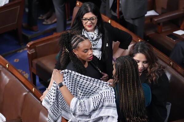 Rep. Summer Lee, D-Pa., dons a scarf, as Rep. Rashida Tlaib, D-Mich., top, looks on, before President Joe Biden arrives to deliver his State of the Union address to a joint session of Congress, at the Capitol in Washington, Thursday, March 7, 2024. (AP Photo/J. Scott Applewhite)