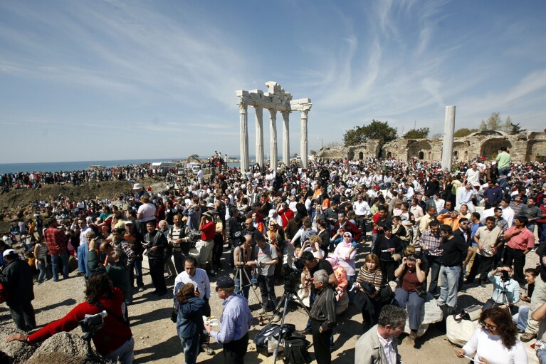 FILE - Thousands of tourists gather to view a solar eclipse in front of Apollo Temple in the Turkish Mediterranean coastal resort of Side, Turkey, Wednesday March 29, 2006.. Astronomers from NASA and Britain's Royal Institute of Astronomy watched the eclipse from an ancient Roman theater. The total solar eclipse began at sunrise on the eastern tip of Brazil, crossesed the Atlantic and made landfall in Ghana, headed north across the Sahara, the eastern Mediterranean, Turkey and the Black Sea, and on into Central Asia, where it will finally die out at sunset in Mongolia. (AP Photo/Burhan Ozbilici, File)