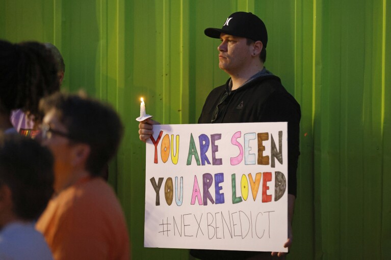 Kody Macaulay holds a sign during a candlelight service for Nex Benedict, a nonbinary teenager who died one day after a fight in a high school bathroom, at Point A Gallery, Saturday, Feb. 24, 2024, in Oklahoma City. (Nate Billings/The Oklahoman via AP)