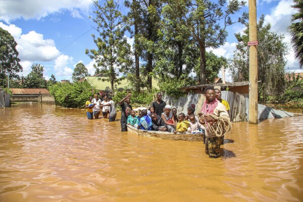 A family uses a boat after fleeing floodwaters that wreaked havoc in the Githurai area of Nairobi, Kenya, Wednesday, April 24, 2024. Heavy rains pounding different parts of Kenya have led to dozens of deaths and the displacement of tens of thousands of people, according to the U.N., citing the Red Cross. (AP Photo/Patrick Ngugi)