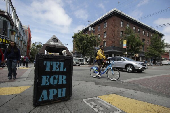 FILE - In this July 18, 2019, file photo, traffic and pedestrians cross Telegraph Avenue in Berkeley, Calif. The politically liberal city of Berkeley in Northern California is considering a proposal to shift traffic enforcement from armed police to unarmed city workers. Supporters say the separation would curb racial profiling and reduce police encounters that can turn deadly, especially for Black motorists. Backers say they believe the proposal before the Berkeley City Council Tuesday, July 14, 2020, is the first of its kind in the U.S. (AP Photo/Jeff Chiu, File)