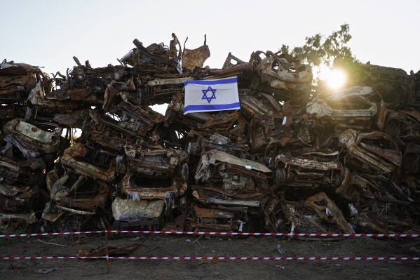 An Israeli flag is placed on a pile of charred vehicles burned in the bloody Oct. 7 cross-border attack by Hamas militants, outside the town of Netivot, southern Israel, Sunday, Jan.7, 2024. (APPhoto/Ohad Zwigenberg)