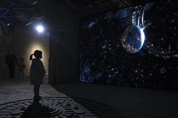 A child watches a video depicting the science fiction universe from a trilogy by Chinese author Liu Cixin in Chengdu, Sichuan province on Saturday, Oct. 21, 2023. The series that began with "The Three-Body Problem" helped Chinese science fiction break through internationally, winning awards and making it onto the reading lists of the likes of former U.S. President Barack Obama and Mark Zuckerberg. (AP Photo/Ng Han Guan)