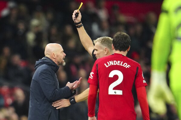 Referee Graham Scott shows a yellow card to Manchester United's head coach Erik ten Hag during the English Premier League soccer match between Manchester United and Luton Town at the Old Trafford stadium in Manchester, England, Saturday, Nov. 11, 2023. (AP Photo/Jon Super)