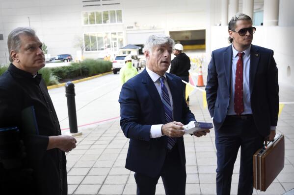 Fr. Paul Kalchik, left,St. Michael's founder and CEO Michael Voris, center, and Milo Yiannopoulos talk with a court officer before entering the federal courthouse, Thursday, Sept. 30, 2021, in Baltimore.  U.S. District Judge Ellen Hollander scheduled a hearing Thursday for the lawsuit that rally planners St. Michael’s Media filed against the city. St. Michael's claims city officials cancelled the Nov. 16 rally because they disapprove of the group's religious message. 
 (AP Photo/Gail Burton)