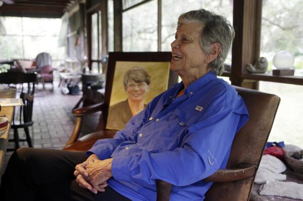 FILE - Maggy Reno Hurchalla, the sister of former U.S. Attorney General Janet Reno, in painting at left, talks during an interview at the family home in Miami, Fla., Monday, Nov. 7, 2016. Hurchalla, an environmentalist who fought to protect Florida's wetlands and was a staunch supporter of her sister Janet Reno, has died on Saturday, Feb. 19, 2022, at age 81. The nonprofit group Friends of the Everglades confirmed Hurchalla's death, calling her a legend. (AP Photo/Lynne Sladky, File)