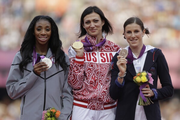 FILE - Russia's Natalya Antyukh, middle, holds the gold medal, United States' Lashinda Demus, left, the silver medal, and Czech Republic's Zuzana Hejnova the bronze medal during a ceremony for the women's 400 hurdles in the Olympic Stadium at the Summer Olympics in London, Aug. 9, 2012. Demus is to be presented in Paris this summer the gold for the race, which was stripped from Antyukh for doping. Demus, now 41 and the mother of four boys, said so much time had passed that she wasn't all that excited when she learned last year that the medal would go to her. (AP Photo/Matt Slocum, FIle)