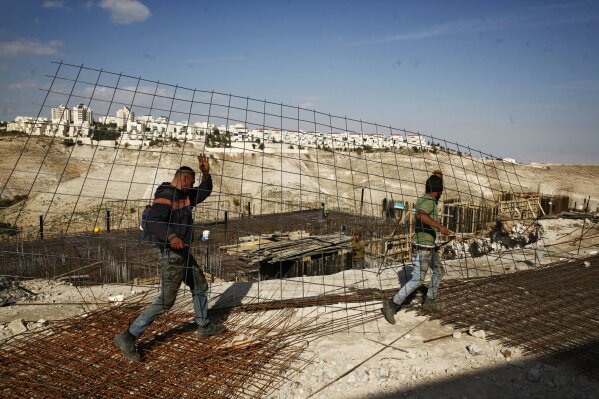 
              FILE - In this Jan. 22, 2017 file photo, workers carry material at a construction site in the West Bank settlement of Maaleh Adumim. Israeli Defense Minister Avigdor Lieberman said Thursday, May 24, 2018, that he will seek approval next week to fast-track construction of 2,500 new West Bank settlement homes this year and advance 1,400 more units that are currently in the planning stage. Senior Palestinian official Hanan Ashrawi condemned Lieberman’s announcement as “Israeli colonialism, expansionism and lawlessness” and called on the International Criminal Court in The Hague, Netherlands, to launch an investigation. (AP Photo/Mahmoud Illean, File)
            