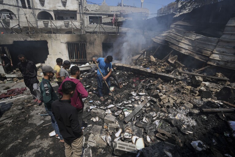 Palestinians search debris after an Israeli strike on a school run by UNRWA, the U.N. agency helping Palestinian refugees, in Nuseirat, Gaza Strip, Tuesday, May 14, 2024. (AP Photo/Abdel Kareem Hana)