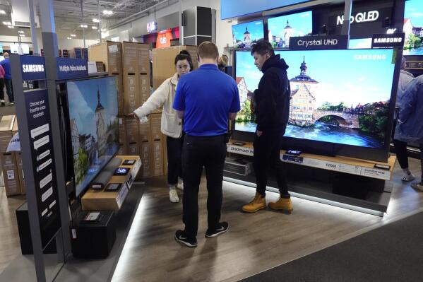 FILE - A Best Buy employee helps customers with a television selection on Friday, Nov. 26, 2021, in Indianapolis.   (AP Photo/Darron Cummings, File)