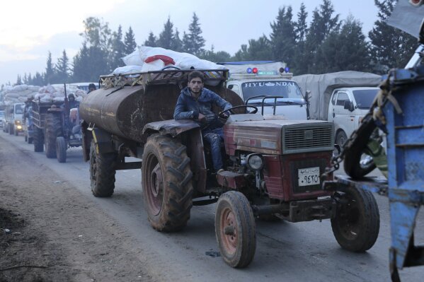 A man pulls a tanker trailer as civilians flee a Syrian military offensive in Idlib province on the main road near Hazano, Syria, Tuesday, Dec. 24, 2019. Syrian forces launched a wide ground offensive last week into the northwestern province of Idlib, which is dominated by al-Qaida-linked militants. The United Nations estimates that some 60,000 people have fled from the area, heading south, after the bombings intensified earlier this month. (AP Photo/Ghaith al-Sayed)