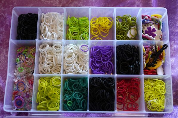 Colorful rubber bands sit is a plastic container Wednesday, Dec. 2, 2020, waiting for Hayley Orlinsky to make them into bracelets in the bedroom of her Chicago home. The 7-year-old has spent most of the coronavirus pandemic crafting the bracelets as a fundraiser, earning nearly $20,000, to buy personal protective equipment for the Ann and Robert H. Lurie Children's Hospital. (AP Photo/Charles Rex Arbogast)
