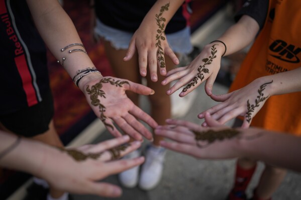 F1 fans show off their henna tattoos made by Bahraini artists at the Formula One Bahrain Grand Prix Village at the Bahrain International Circuit in Sakhir, Bahrain, Saturday, April 12, 2025. (AP Photo/Altaf Qadri)