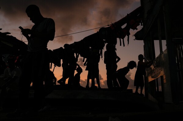 Migrantes se relajan al atardecer en la isla de Gardi Sugdub, en la costa caribeña de Panamá, el 23 de febrero de 2025, donde pasaron la noche antes de intentar tomar barcos hacia Colombia, un día después de regresar desde el sur de México, tras abandonar sus esperanzas de llegar a Estados Unidos debido a la campaña antiinmigración del presidente Donald Trump. (AP Foto/Matias Delacroix)