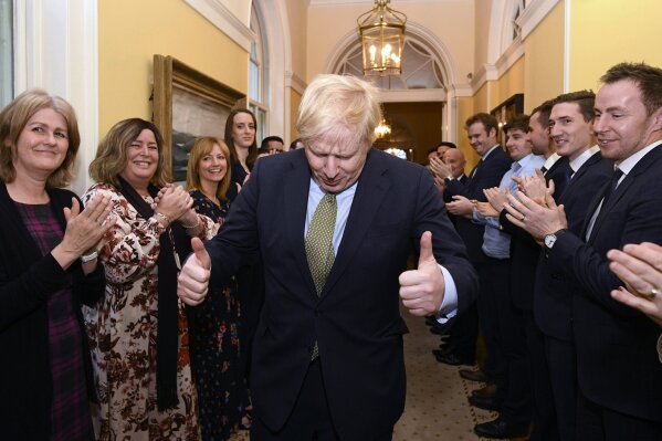 Britain's Prime Minister Boris Johnson is greeted by staff as he returns to 10 Downing Street, London, after meeting Queen Elizabeth II at Buckingham Palace and accepting her invitation to form a new government, Friday Dec. 13, 2019.  Boris Johnson led his Conservative Party to a landslide victory in Britain’s election that was dominated by Brexit. (Stefan Rousseau/PA via AP)