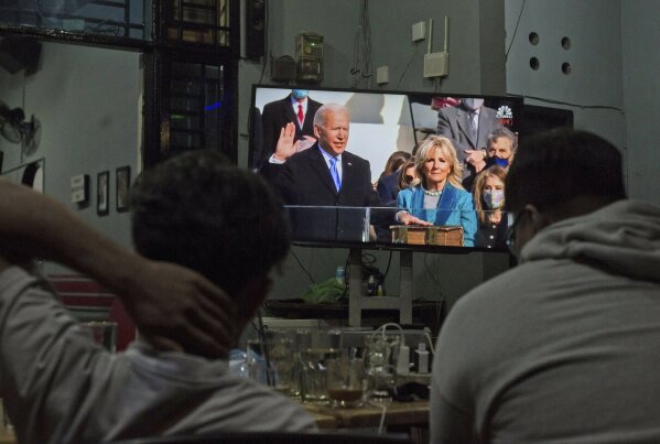 People watch the inauguration of U.S. President Joe Biden on a television at a coffee shop in Medan, North Sumatra, Indonesia, late Wednesday, Jan. 20, 2021. (AP Photo/Binsar Bakkara)