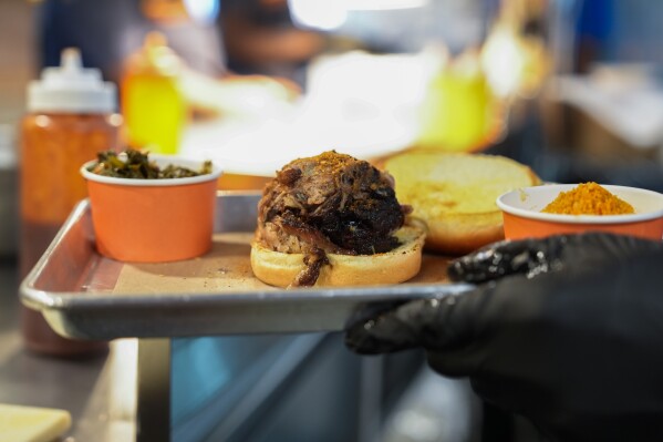 A line cook carries a pulled pork sandwich Wednesday, June 12, 2024, at a barbecue restaurant in Cincinnati. Psychologists have known for years now that men tend to eat more meat than women, but a study of people around the world now reveals that that's true across cultures. (AP Photo/Joshua A. Bickel)