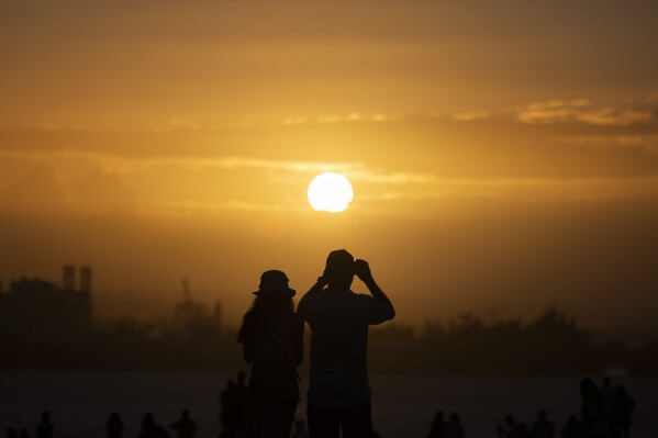 FILE - People gather at "El Morro" to watch the sunset during the San Sebastián Street festivities in San Juan, Puerto Rico, Jan. 21, 2024. For the eighth straight month, Earth was record hot, according to the European climate agency’s analysis of January 2024. (AP Photo/Alejandro Granadillo, File)