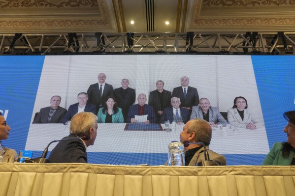 Pro-Kurdish Peoples' Equality and Democracy Party, or DEM, delegation members release an statement from the jailed leader of the rebel Kurdistan Workers' Party, or PKK, Abdullah Ocalan, center at the background photo, in Istanbul, Turkey, Thursday, Feb. 27, 2025. (AP Photo/Khalil Hamra)