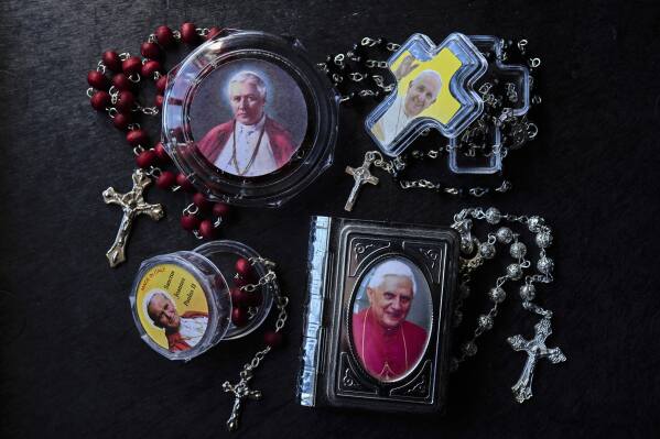From top left and clockwise: boxes of rosaries with pictures of Pope Pius X, Pope Francis, John Paul II, and Pope Benedict XVI in Rome, Thursday, May 1, 2025. (AP Photo/Bernat Armangue)