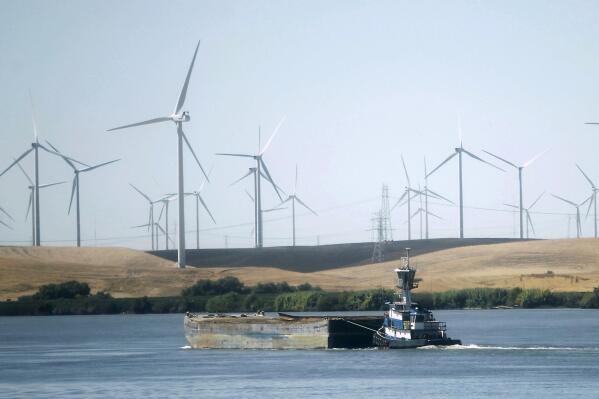 FILE - A tugboat pushes a barge down the Sacramento River past wind turbines near Rio Vista, Calif., on Monday, Sept. 23, 2013. The Biden administration announced, Thursday, May 26, 2022, that it's opening a proposed notice of sale for five leases off of Morro and Humboldt Bays along California's central and northern coasts. The projects would be the first offshore wind farms on the U.S. Pacific Coast. (AP Photo/Rich Pedroncelli, File)