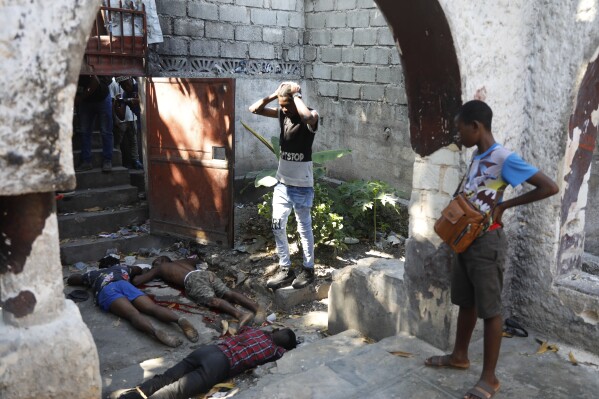 People look at the the bodies of three persons shot dead after an overnight shooting in the Pétion Ville neighborhood of Port-au-Prince, Haiti, Monday, April 1, 2024.(AP Photo/Odelyn Joseph)