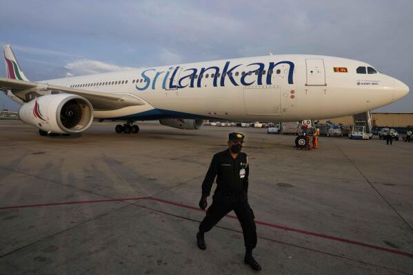 A Sri Lankan Airlines plane carrying remains of Priyantha Kumara, a Sri Lankan employee who was lynched by a Muslim mob in Sialkot arrives as a security officers guards the area in Colombo, Sri Lanka, Dec. 6, 2021. Sri Lanka’s prime minister on Monday proposed to privatize the country’s loss-making national carrier as part of reforms to solve the country worst economic crisis in recent memory. (AP Photo/Eranga Jayawardena, File)