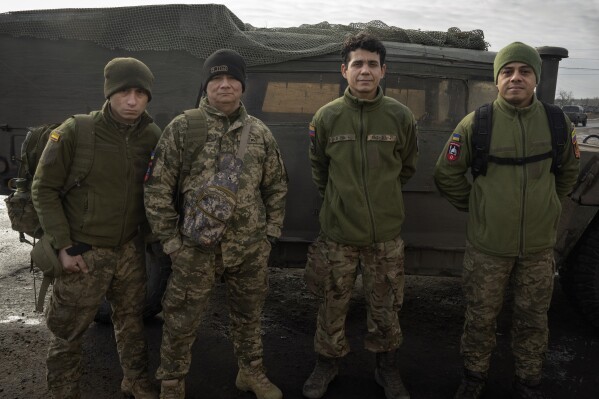 Colombian veterans who joined the Ukrainian armed forces to help fight Russia pose for a photo near their Humvee on the front line near Lyman, Donetsk region, Ukraine, Monday, Jan. 29, 2024. After two years of war, Ukraine is looking for ways to replenish its depleted ranks. The Colombian professional soldiers are a welcome addition. (AP Photo/Efrem Lukatsky)