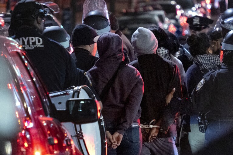 Policjanci z Nowego Jorku zatrzymują ludzi w pobliżu kampusu Uniwersytetu Columbia w Nowym Jorku po oczyszczeniu budynku i obozowiska przejętego przez protestujących, wtorek, 30 kwietnia 2024 r.  (AP Photo/Craig Ruttle)