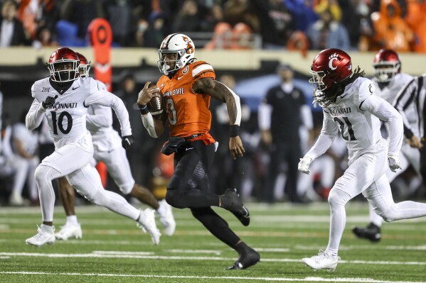 Oklahoma State running back Ollie Gordon II (0) runs past Cincinnati safety Bryon Threats (10) and defensive back Kalen Carroll (21) during the second half of an NCAA college football game Saturday, Oct. 28, 2023, in Stillwater, Okla. (AP Photo/Mitch Alcala)