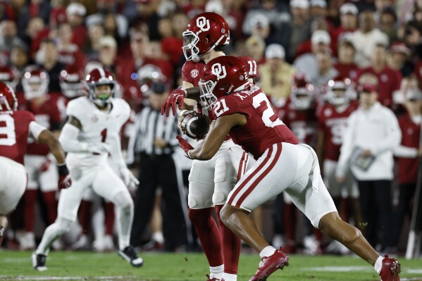 Oklahoma quarterback Jackson Arnold (11) hands off the ball to Oklahoma running back Xavier Robinson (21) during the first quarter of a NCAA college football game against Alabama on Saturday, Nov. 23, 2024, in Norman, Okla. (AP Photo/Alonzo Adams)