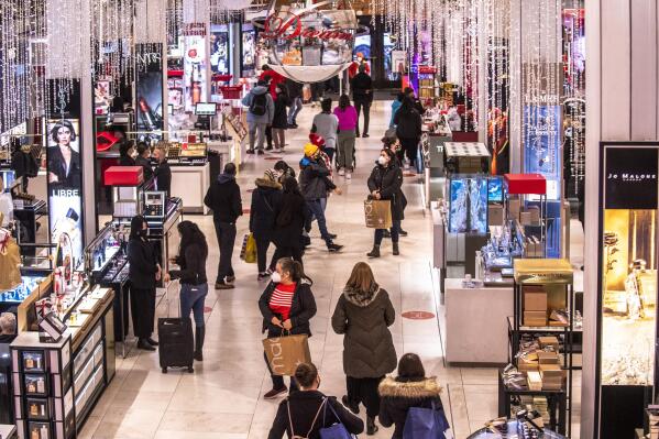 FILE - Shoppers walk through Macy's  on Nov. 26, 2021, in New York.  Americans slowed their spending from November to December as a trifecta of product shortages, surging prices and a surge of the highly contagious omicron curtailed spending. Retail sales fell 1.9% in December compared with the previous month when sales increased 0.3%, the U.S. Commerce Department said Friday, Jan. 14, 2022. (AP Photo/Brittainy Newman, File)