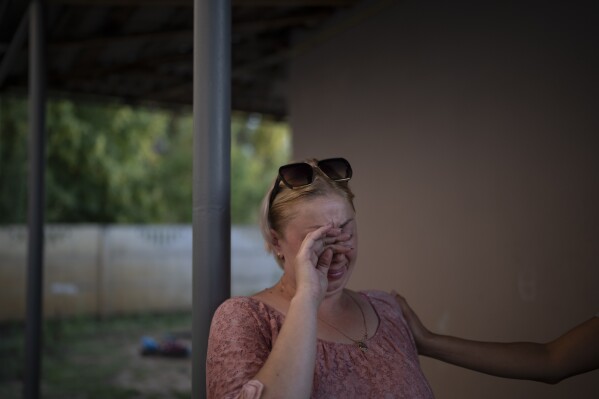 Natalia Rosolova cries outside her home in Kupiansk-Vuzlovyi, Ukraine, Wednesday, Aug. 23, 2023. (AP Photo/Bram Janssen)
