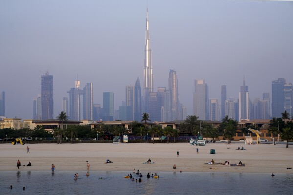 With the city skyline and Burj Khalifa, world's tallest building in background, people enjoy swimming in Dubai, United Arab Emirates, Wednesday, July 5, 2023. (AP Photo/Kamran Jebreili)