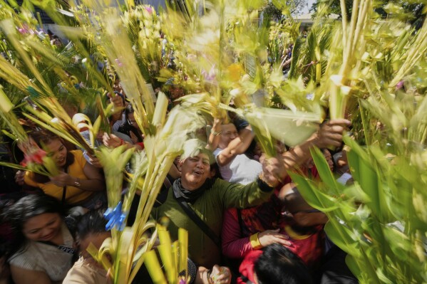Devotees wave their palm fronds during blessing rites outside the Cathedral in Antipolo, Philippines, as they observe Palm Sunday, April 13, 2025. (AP Photo/Aaron Favila)