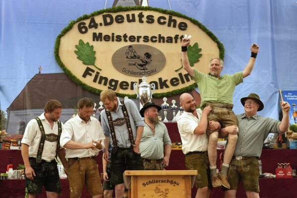 Competitors celebrates after their bouts while they try to pull the opponents over the table at the German Championships in Fingerhakeln or finger wrestling, in Pang, near Rosenheim, Germany, Sunday, April 27, 2025. (AP Photo/Matthias Schrader)