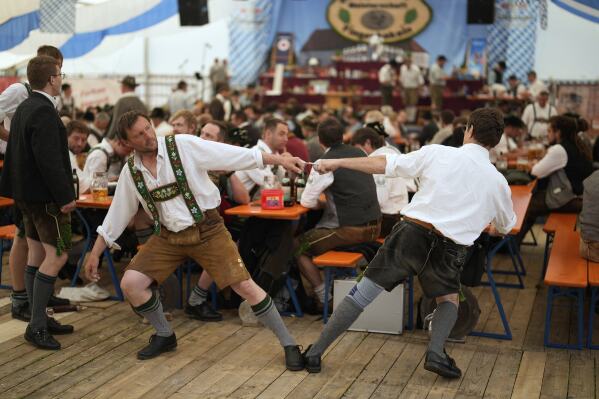 Competitors warm up for their bout while they try to pull the opponent over the table at the German Championships in Fingerhakeln or finger wrestling, in Pang, near Rosenheim, Germany, Sunday, April 27, 2025. (AP Photo/Matthias Schrader)