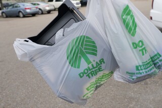 FILE - A customer exits a Dollar Tree store holding a shopping bag on Wednesday, May 11, 2022, in Jackson, Miss. Dollar Tree says it plans to close nearly 1,000 stores and moved to a surprise loss in its fiscal fourth quarter as the discount retailer took a $1.07 billion goodwill impairment charge. Shares dropped more than 7% before the market open on Wednesday, March 13, 2024. (AP Photo/Rogelio V. Solis, File)