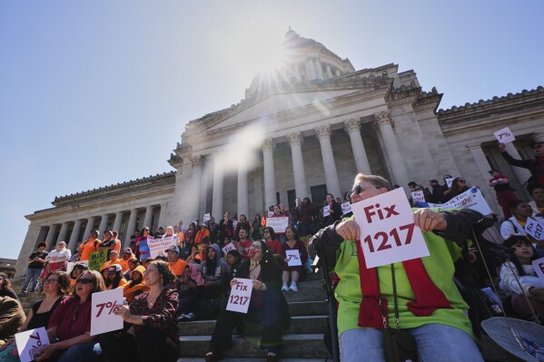 People gather on the steps of the Washington State Capitol Building during a rally advocating for lawmakers to change and pass House Bill 1217, a rent-control bill, Friday, April 18, 2025, in Olympia, Wash. (AP Photo/Lindsey Wasson)