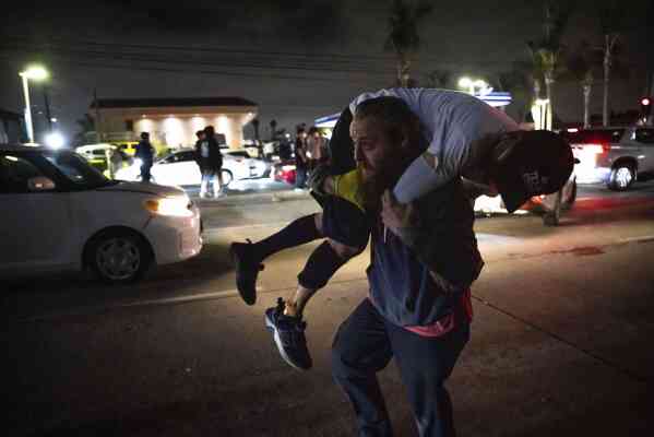 A person carries an injured protester to cover during a protest in Compton, Calif., Saturday, June 7, 2025, after federal immigration authorities conducted operations. (AP Photo/Ethan Swope)