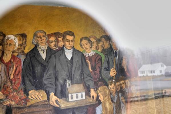 A fresco depicting community members with a model of South Solon Meeting House is seen through a window in the lobby of the building, Sunday, April 6, 2025, in Solon, Maine. (AP Photo/Robert F. Bukaty)