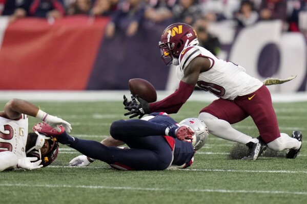 Washington Commanders safety Jartavius Martin, top right, intercepts a pass intended for New England Patriots wide receiver JuJu Smith-Schuster, center, as Commanders cornerback Kendall Fuller, left, defends in the second half of an NFL football game, Sunday, Nov. 5, 2023, in Foxborough, Mass. (AP Photo/Charles Krupa)