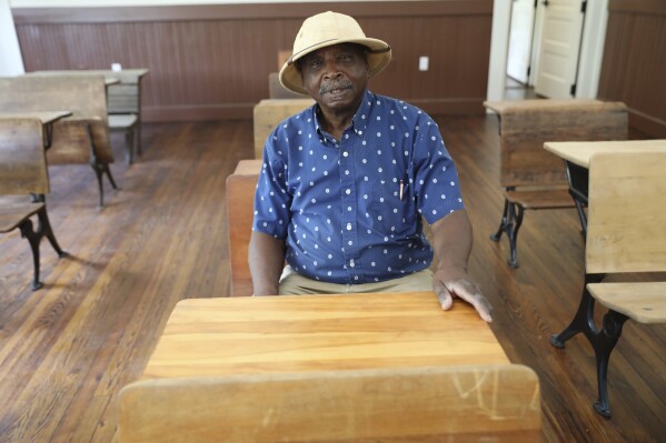 Ralph James sits in a classroom at a restored Rosenwald School made to look like it did when the school was open in St. George, S.C., on Tuesday, July 11, 2023. Jewish businessman Julius Rosenwald donated money to help build 5,000 schools for Black students across the American South a century ago. Only about 500 are standing and roughly half of them have been restored. (AP Photo/Jeffrey Collins)