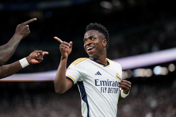 FILE - Real Madrid's Vinicius Junior celebrates after scoring his side's first goal during a Spanish La Liga soccer match between Real Madrid and Celta Vigo at the Santiago Bernabeu stadium in Madrid, Spain, on March 10, 2024. Real Madrid has filed a complaint with Spanish state prosecutors asking them to investigate the reported racist chants aimed at forward Vinícius Júnior outside the stadiums of Atletico Madrid and Barcelona before their Champions League games this week. Madrid said Friday March 15, 2024 that it asked the prosecutors to request footage from security cameras outside the two stadiums in order to “identify the authors of the racist insults and hate speech.” (AP Photo/Manu Fernandez, File)