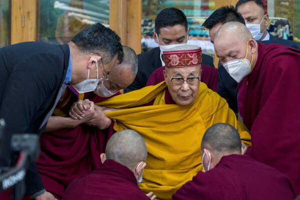 Tibetan spiritual leader the Dalai Lama is helped by attending monks after he addressed a group of students at the Tsuglakhang temple in Dharamshala, India, Tuesday, Feb. 28, 2023. (AP Photo/Ashwini Bhatia)