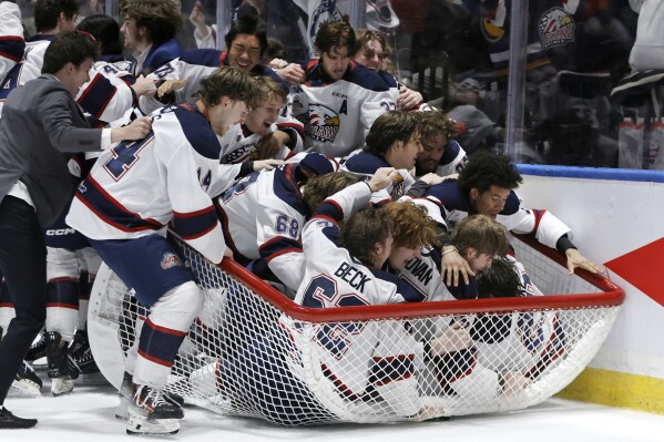 The Saginaw Spirit team piles into a goal after winning the Memorial Cup hockey final against the London Knights in Saginaw, Mich., Sunday, June 2, 2024. (Duane Burleson/The Canadian Press via AP)