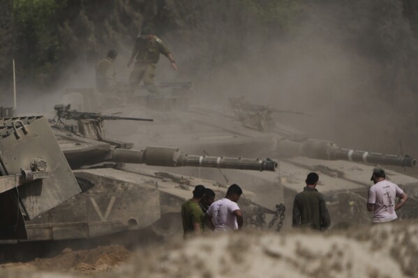 Israeli soldiers work on tanks at a staging area near the border with the Gaza Strip, in southern Israel, Sunday, May 18, 2025. (AP Photo/Ariel Schalit)