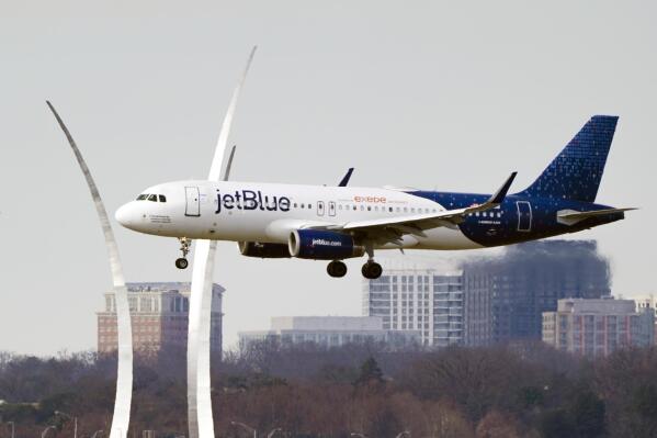 FILE - A JetBlue passenger flight passes the Air Force Memorial as it prepares to land at Reagan Washington National Airport in Arlington, Va., across the Potomac River from Washington, Wednesday,  Jan. 19, 2022.   Air travel is expected to make close to a full recovery in 2022, and for airlines looking to take advantage of the rebound, size matters. Fleet size is a key motive for JetBlue’s bid to woo budget carrier Spirit Airlines and break up that company’s deal with rival Frontier.   (AP Photo/J. Scott Applewhite, File)