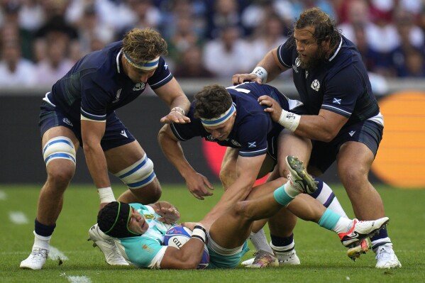 South Africa's Cheslin Kolbe, bottom, is tackled by Scotland's Jamie Ritchie, left, and Scotland's Rory Darge, center, during the Rugby World Cup Pool B match between South Africa and Scotland at the Stade de Marseille in Marseille, France, Sunday, Sept. 10, 2023. (AP Photo/Daniel Cole)
